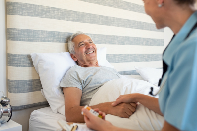cheerful senior man lying on bed receiving health care