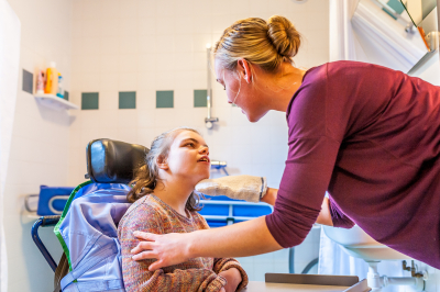 disabled child in a wheelchair being cared for by a special needs care assistant